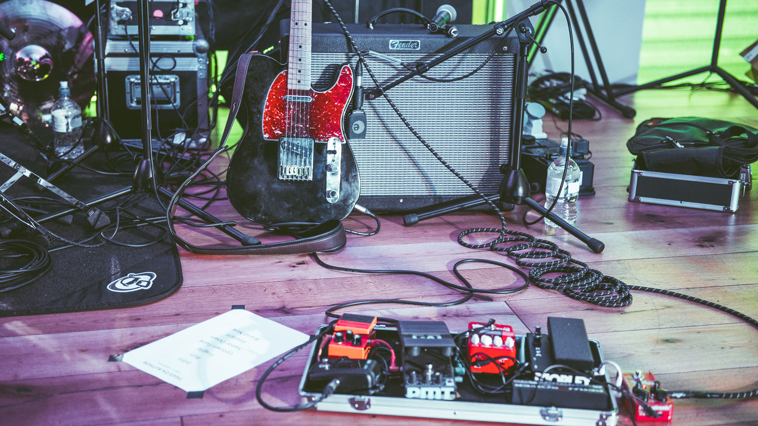 A guitar, amp and pedals on a stage ready for a gig
