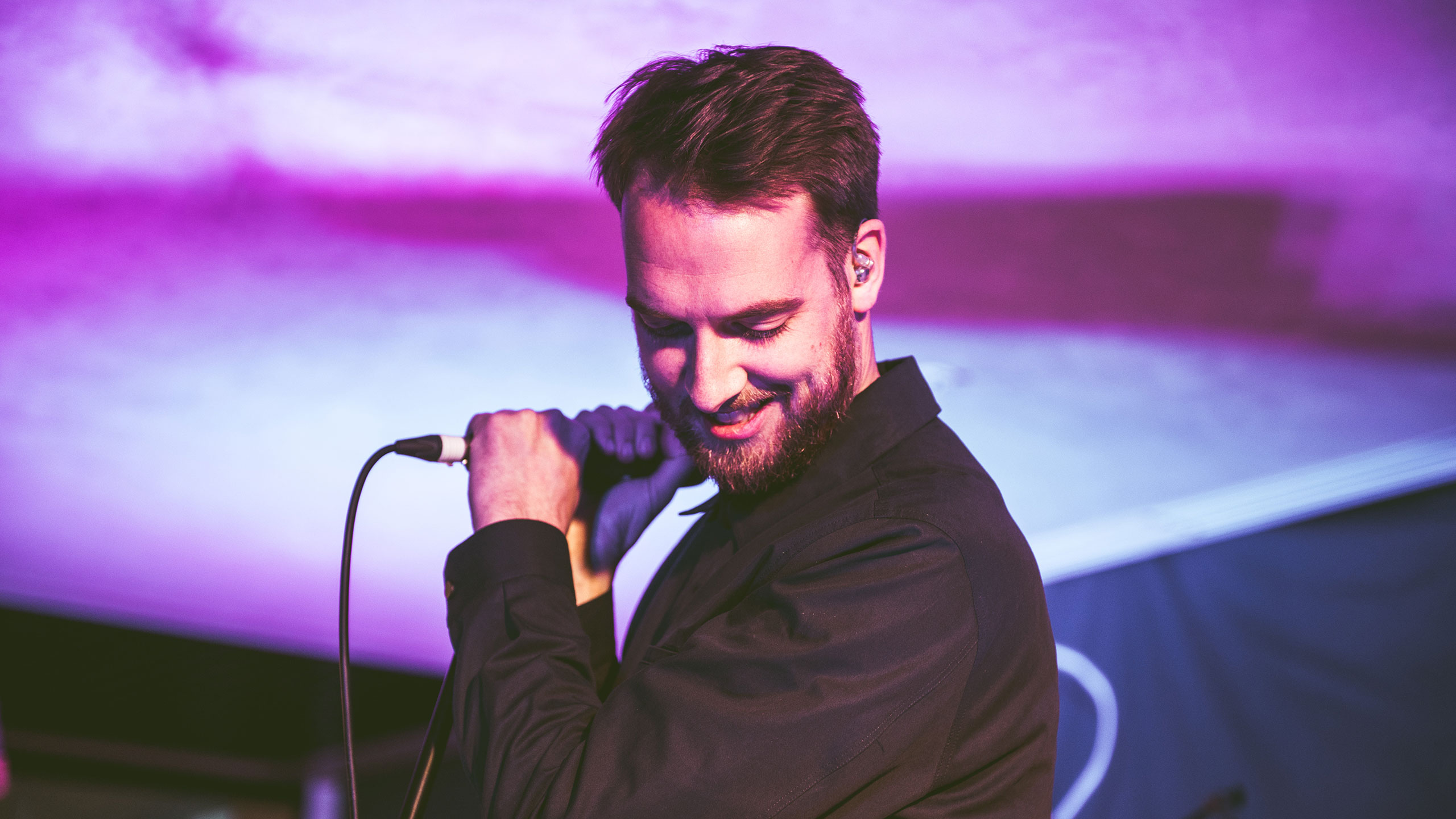 Honne's Andy Clutterbuck looks down and smiles on stage at PRS Presents