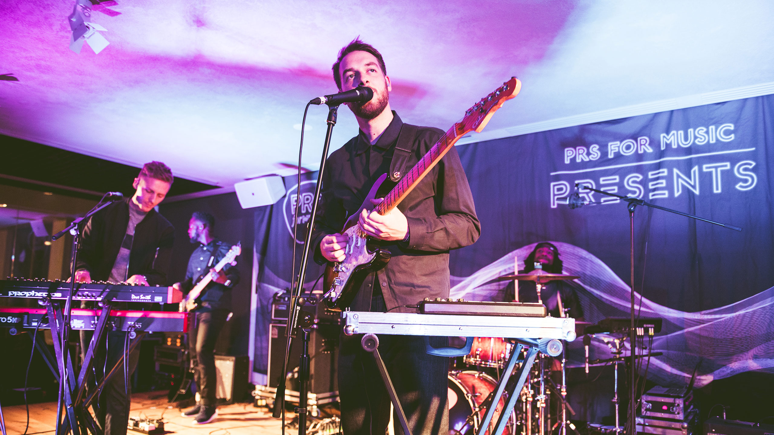 Honne perform guitar, vocals and synth with a bass player and drummer, on stage at PRS Presents