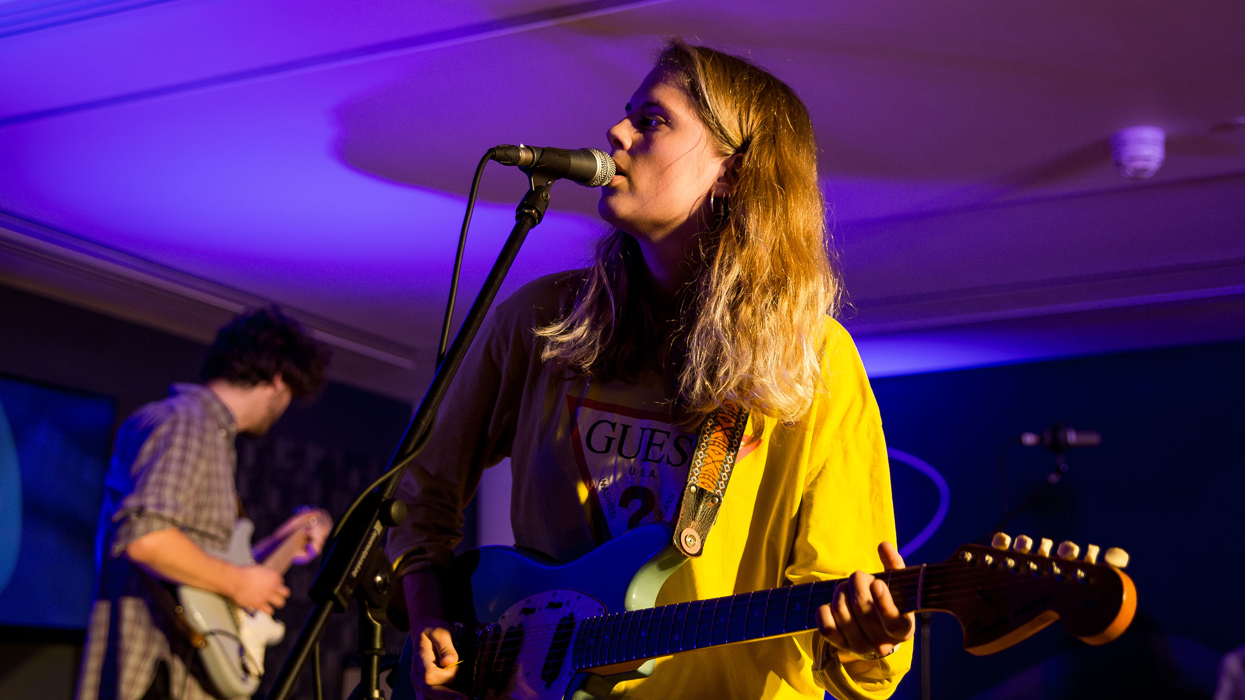 Marika Hackman plays guitar and sings, wearing a yellow shirt, on stage at PRS for Music Presents