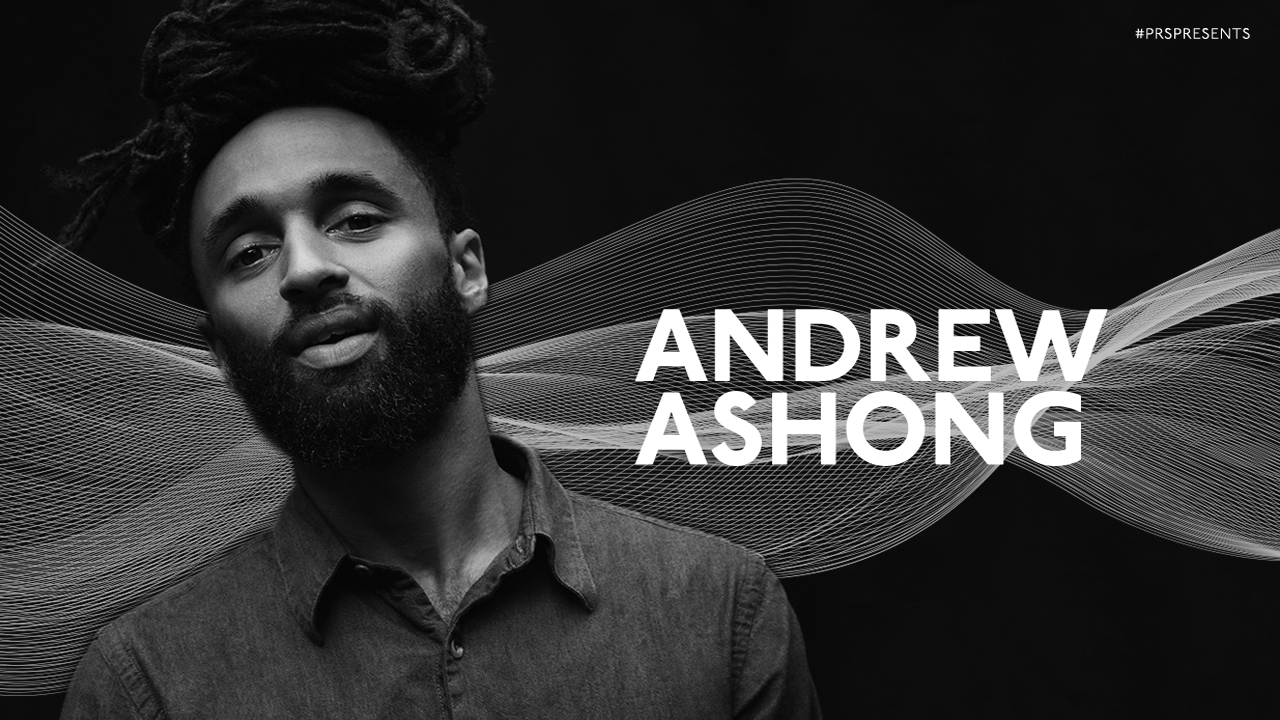 A black and white image of Andrew Ashong, wearing a dark shirt, looking at the camera, with a graphic background for PRS for Music Presents