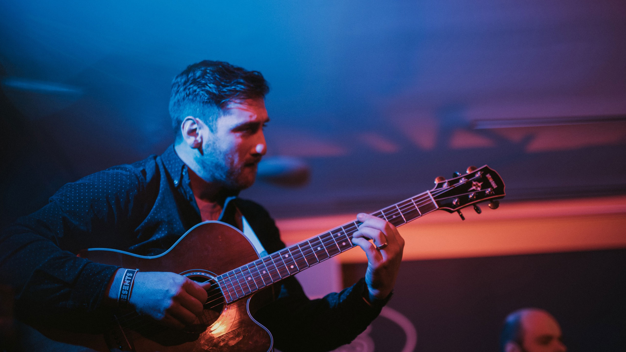 A member of Dr Meaker plays acoustic guitar on stage at PRS for Music Presents