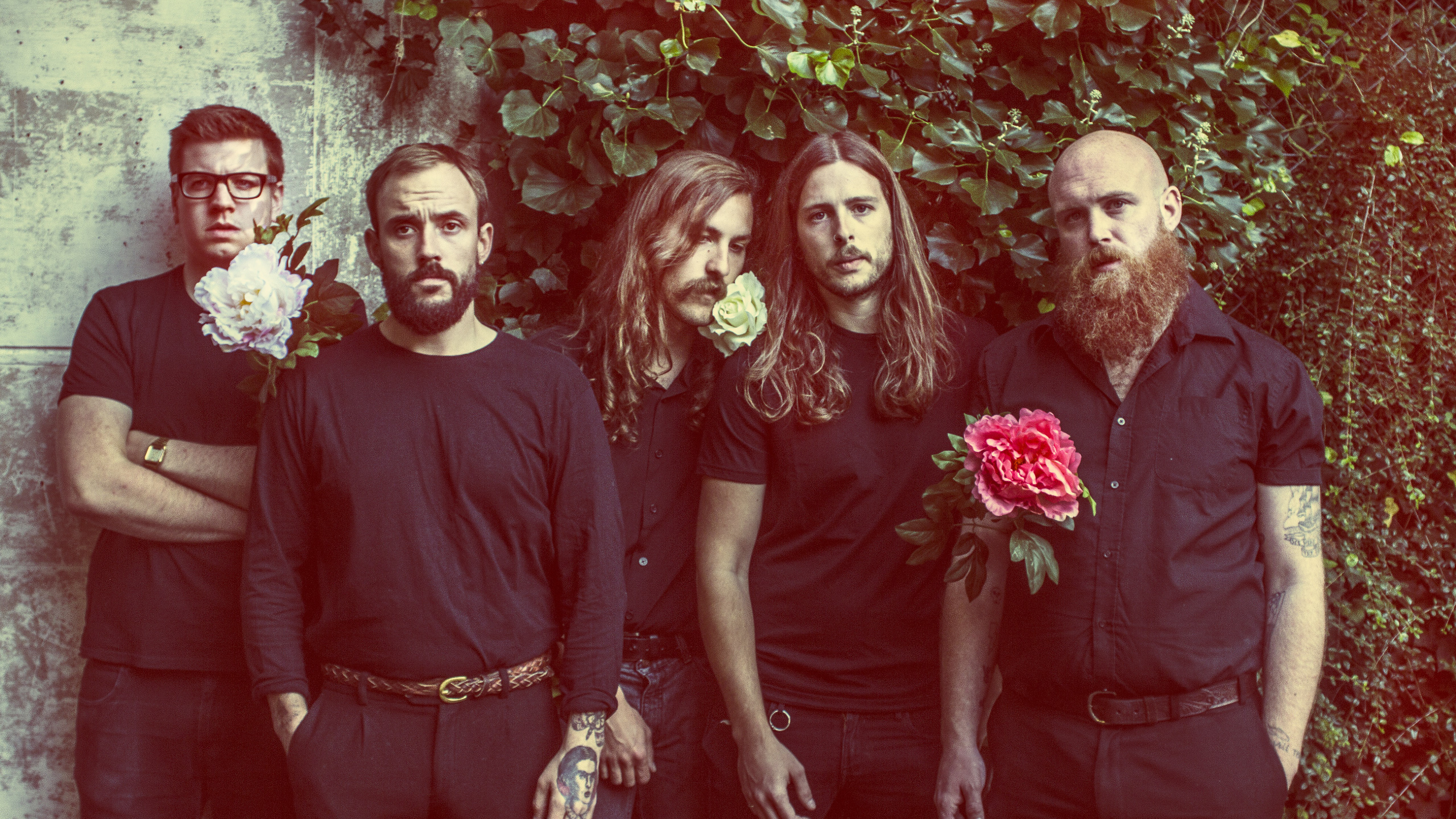 Idles pose in front of a bush holding flowers
