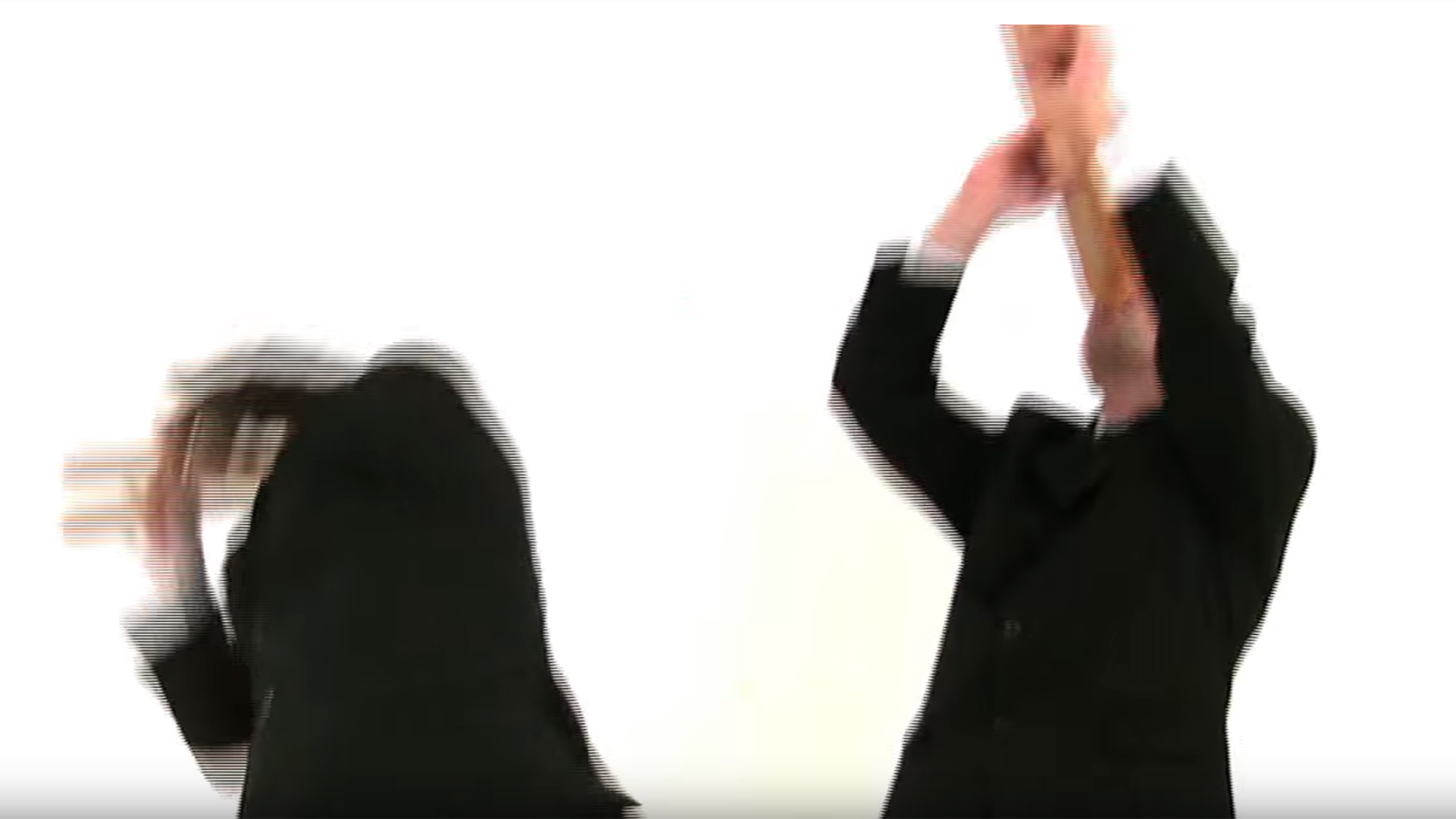 Two men in black suits play baguettes like trumpets